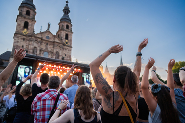 Eine Menschenmenge jubelt vor einer Bühne am Domplatz in Fulda.