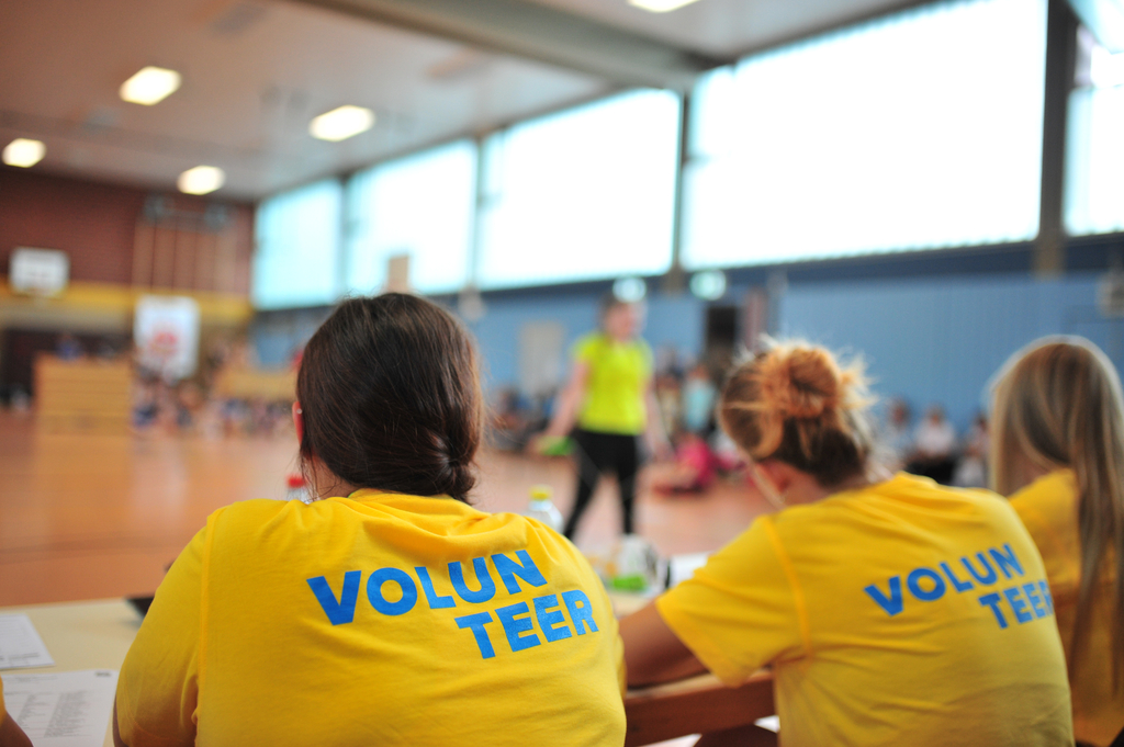 Mehrere Personen mit einem Volunteer-Shirt sitzen an einem Tisch.
